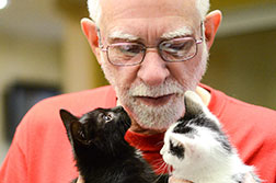 Photo of a man holding two kittens.